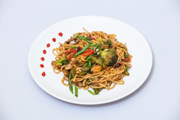 Wok food on a white ceramic plate is tasty and fresh with sauce on a light isolated background