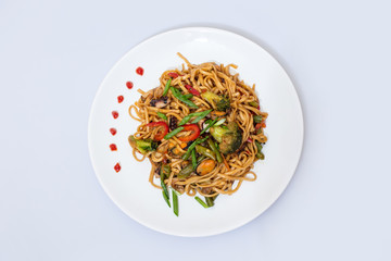 Wok food on a white ceramic plate is tasty and fresh with sauce on a light isolated background