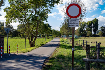 Red sign beside a small street with the german lettering "Landwirtschaftlicher Verkehr frei" meaning agricultural traffic free
