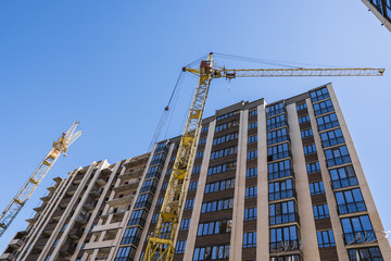 Construction of a high-rise building with a crane. Building construction using formwork. Cranes and buildings against the blue sky.