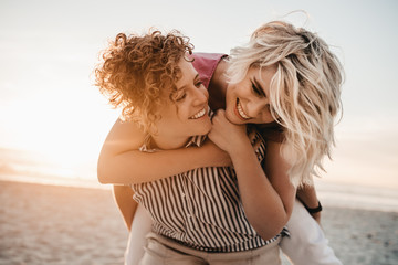Laughing lesbian couple having fun together at the beach