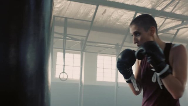 fitness woman athlete training kickboxing exercise workout punching bag fierce sportswoman exhausted resting after practice in gym wearing boxing gloves close up