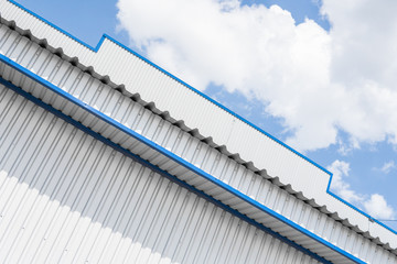 Industrial construction of Metal white sheet and blue corners. Roof sheet metal or corrugated roofs of factory building or warehouse.