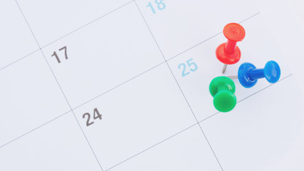 Pin on the date number 25. The twenty-fifth day of the month is marked with a red,green, blue thumbtack.selective focus