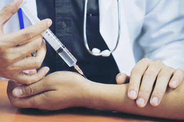Doctor or nurse hands with syringe injecting to wrist medical  from patient arm in hospital. For...