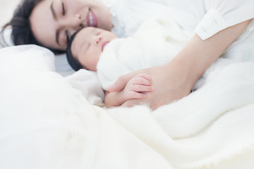 Fototapeta na wymiar Happy beautiful asian woman looking at her sleeping baby child