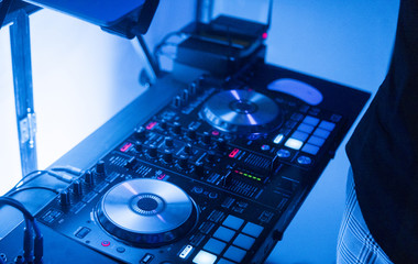 DJ plays and mix music on digital mixer controller. Close-up DJ performance controller, digital midi turntable system, adjustable torque, aluminum-turntable platter, fader, knob and slider, button.