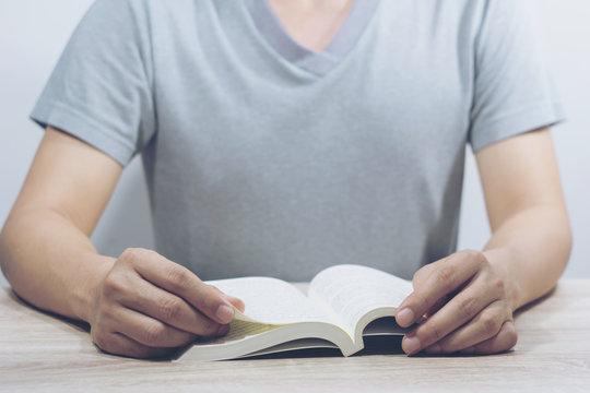 leisure, education, literature and home concept - Young man reading a book   seated on a chair.selective focus - Powered by Adobe
