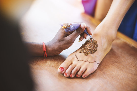 Henna artist (Mehndi) painting the foot of women on the indian wedding day