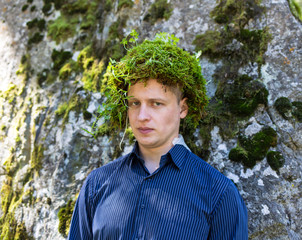 Office worker in a business suit, outdoors with a make-up on his face and green moss on his head....