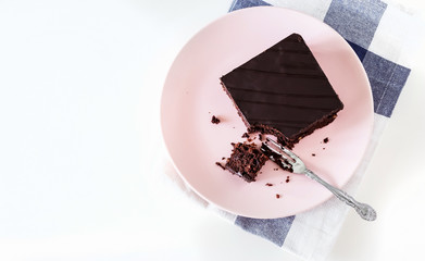 Chocolate vegan brownie cake with nuts. Pink plate. Light background. Selective focus. Top view.
