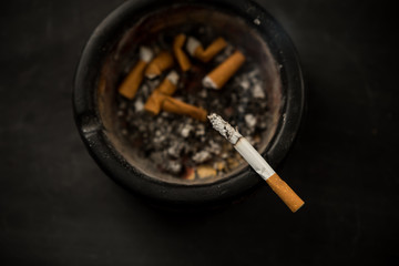 cigarette in an ashtray on a dark background, view from the top
