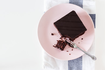 Chocolate vegan brownie cake with nuts. Pink plate. Light background. Selective focus. Top view.