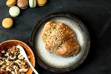 pie with apples and nuts surrounded by nuts and macaroons on a dark, rustic table, top view