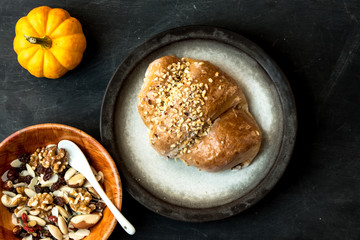 pie with apples and nuts surrounded by nuts and pumpkin on a dark, rustic table. Top view