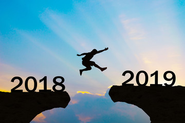 Happy New Year 2019 Men jump over silhouette mountains and sun