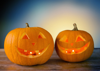 holidays, halloween and decoration concept - close up of carved pumpkins on table over blue background