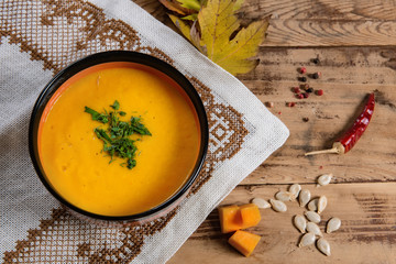 Flat lay pumpkin soup bowl on rustic wooden background