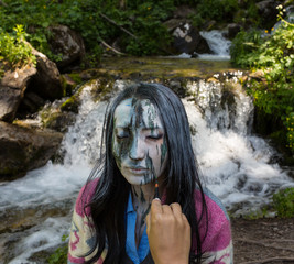 Girl Office worker, outdoors with a makeup on her face imitating a mountain stream. The girl merges...
