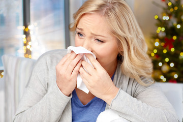 health, holidays and people concept - close up of ill woman blowing nose to paper napkin over...