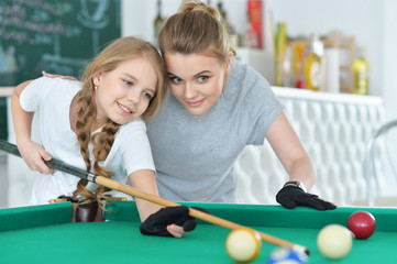 Portrait of cute girl with mother playing billiard