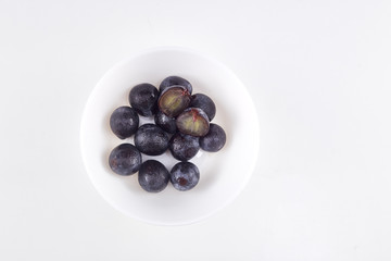 Black grape in bowl on white