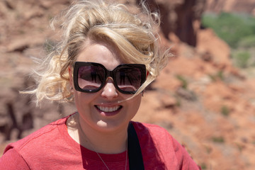 Blonde young adult woman portrait smiles wearing sunglasses. Taken at Arizona's Canyon De Chelly National Monument