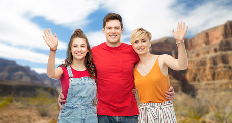 Obraz premium travel, tourism and summer holidays concept - group of happy smiling friends hugging over grand canyon national park background