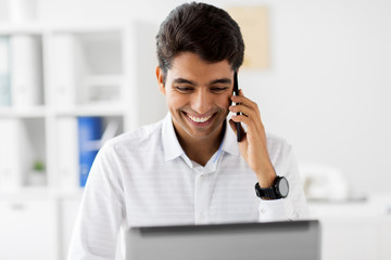 business, people and technology concept - businessman with laptop computer calling on smartphone at...