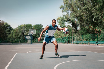 Picture of young confused african basketball player practicing outdoor. Fit afro man in motion and movement. athletic and sport lifestyle concept