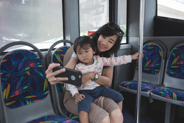 woman is holding her daughter and selfie with smartphone