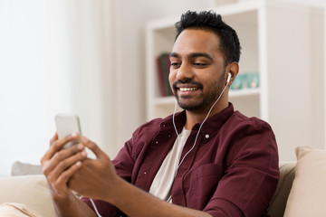 technology, leisure and people concept - happy man in earphones with smartphone listening to music...