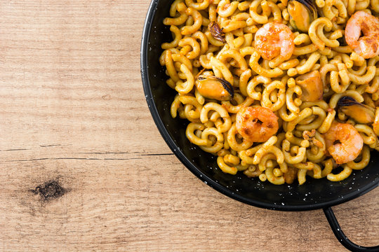 Traditional Spanish fideua. Noodle paella on wooden table. Top view. Copyspace