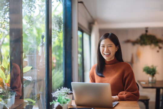 Happy Young Asian Girl Working At A Coffee Shop With A Laptop