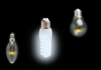 Energy-saving concept of innovation of bright fluorescent lamps, green technology and old dim incandescent bulbs.
