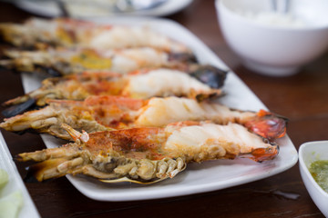 Close up Grilled prawns or fresh grilled shrimps ,cooking seafood with salad on white dish in Thai restaurant. Selective focus