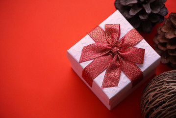 White gift box with red ribbon and pine cone on red background , have space for idea.
