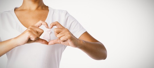 Women making heart shape with their fingers around pink ribbon
