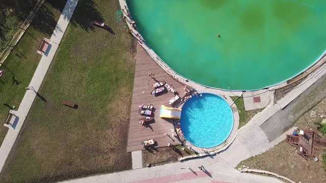 Aerial View Sinking Down And Spinning On Small Children Who Play And Bathe In A Special Children's Pool With A Small Inflatable Water Slide Under The Supervision Of Parents Next To A Large Adult Pool