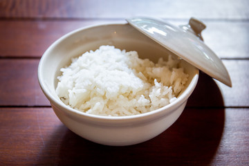Cooked jasmine rice in a bowl on wooden dining table.