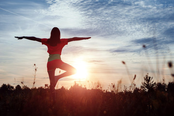Young woman silhouette yoga on nature at sunset. Fresh air, healthy lifestyle, copy space. Magic background
