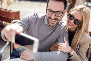 Young couple taking selfie in city cafe