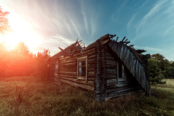 Creative background, an abandoned wooden house, a hut against a beautiful sunset. The concept of a...