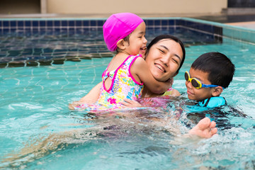 family spent time to swim in swimming pool. they enjoy playing together with laughing