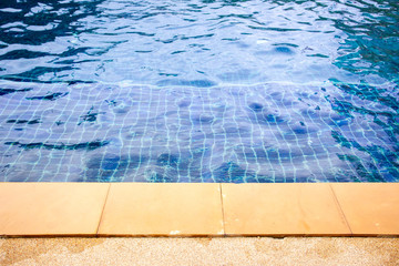 Photograph of a swimming pool edge in resort with full of water.