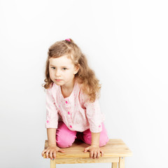 Cute little child sitting on the chair and smiling. wearing pink clothes. Portrait of adorable baby girl