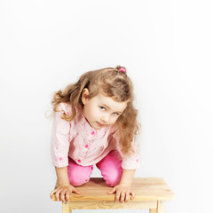 Cute little child sitting on the chair and smiling. wearing pink clothes. Portrait of adorable baby girl