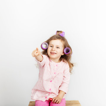 Beautiful little girl with curlers on her head looking at camera and having fun at home. Day off, holiday, day of rest, free, off-time. fashion baby girl
