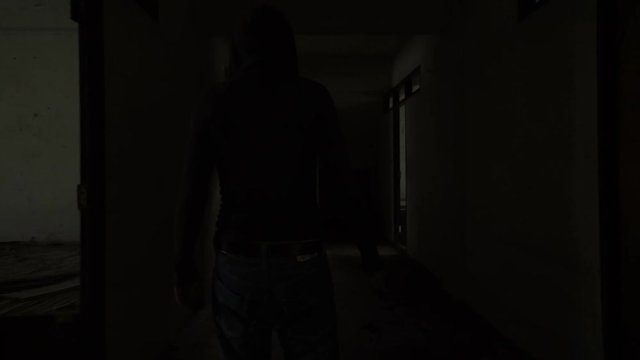 Silhouette of a man carry a knife walking in an Abandoned house
