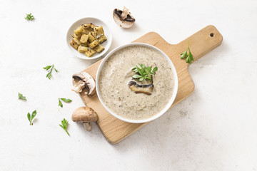 mushroom cream soup with herb garnish and croutons on a light  background with copy space, high angle view from above